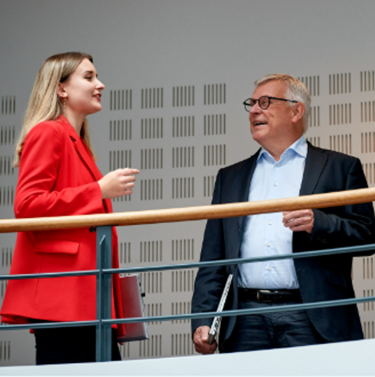 Two professionals in discussion on an indoor office balcony, highlighting collaboration and expert consultation for marine and energy solutions.