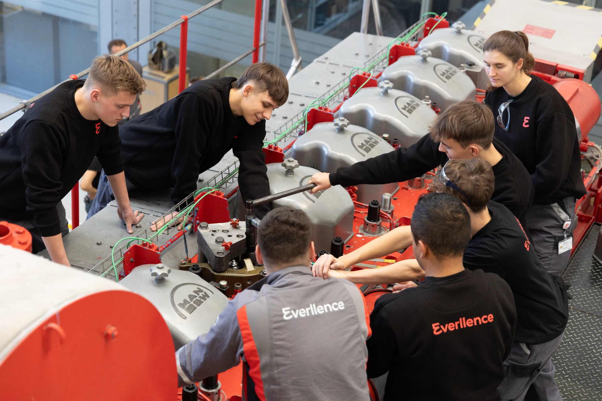 Group of students working together on mechanical engineering equipment during practical training.