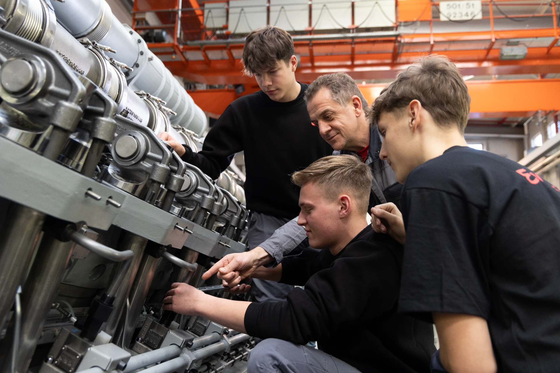Auszubildende arbeiten gemeinsam an einer komplexen industriellen Anlage.