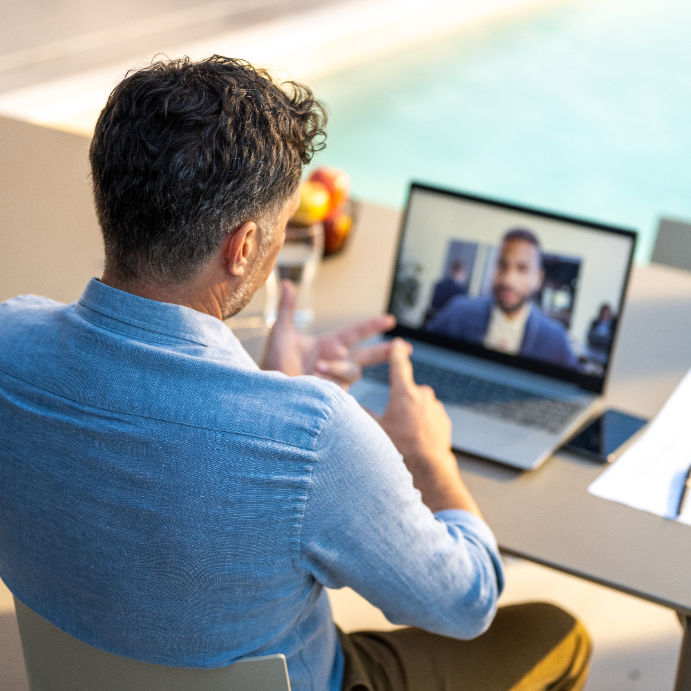 back of person in a meeting next to pool in front of a laptop