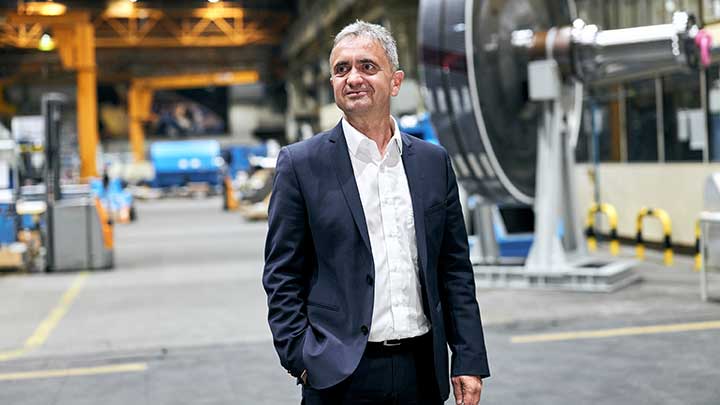 Uwe Lauber (CEO) standing in an industrial hall with a blurred background.