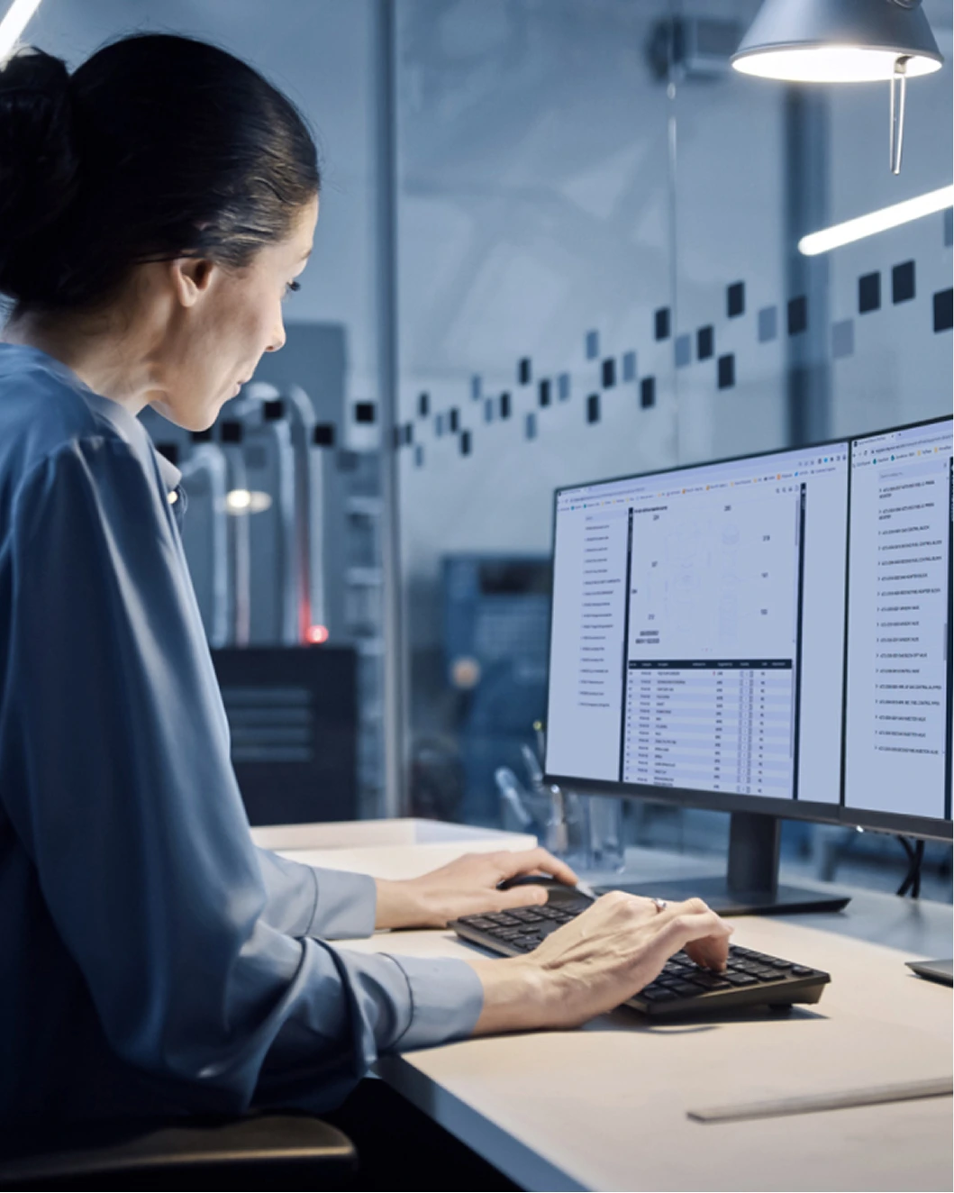 woman sitting at a desk in front of two computer screens