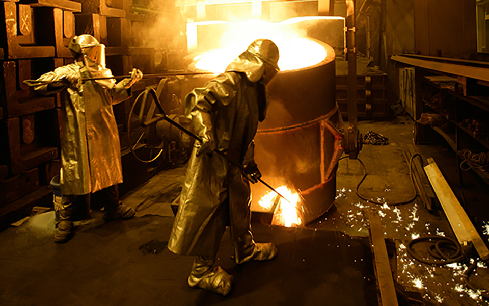 Foundry workers in protective gear during casting