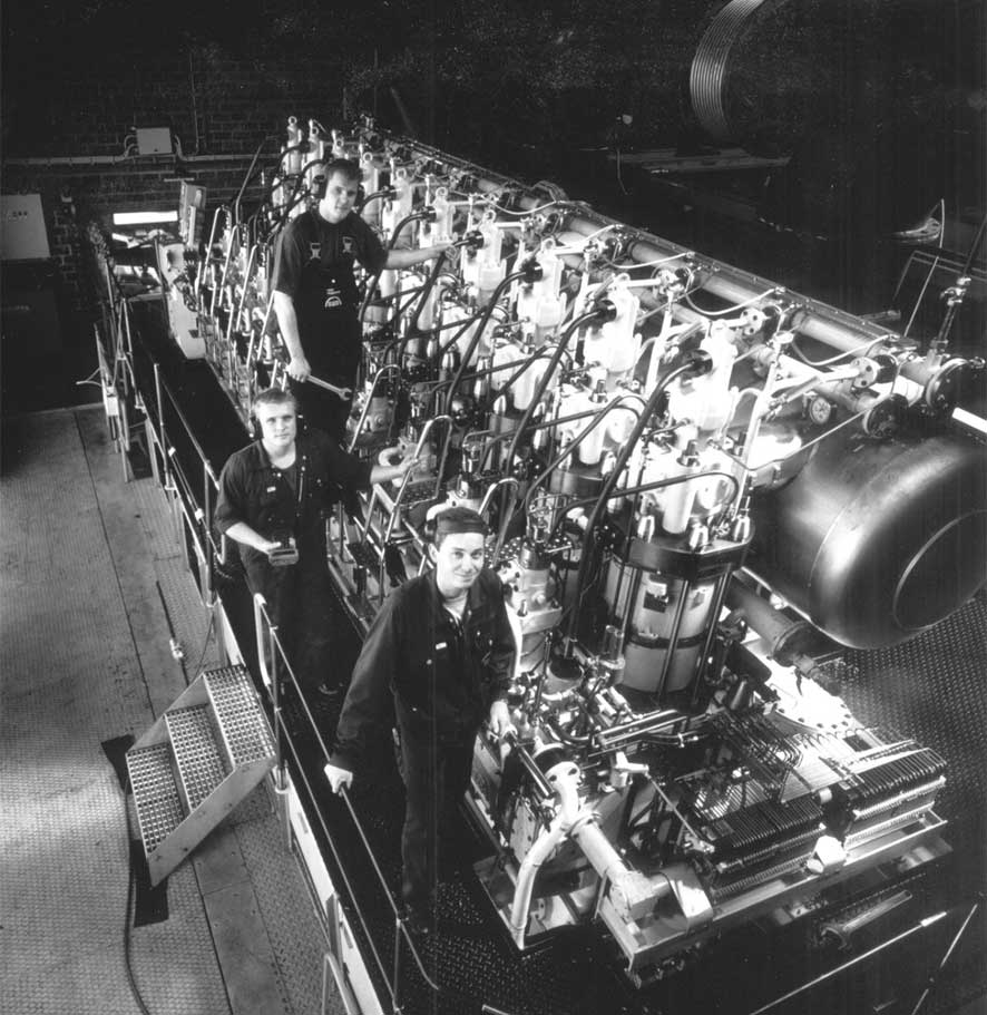 historical photo of 3 workers stanging on an marine engine