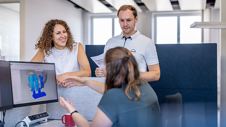 three employees talking while looing at a screen