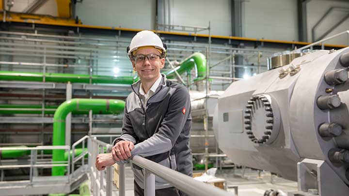 Karl Böhle smiling next to compressor unit in esbjerg heat pump plant