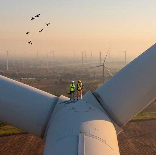 two workers standing on a wind turbine