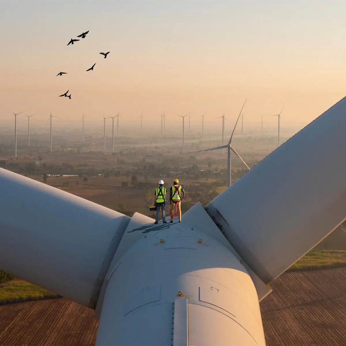two workers standing on a wind turbine