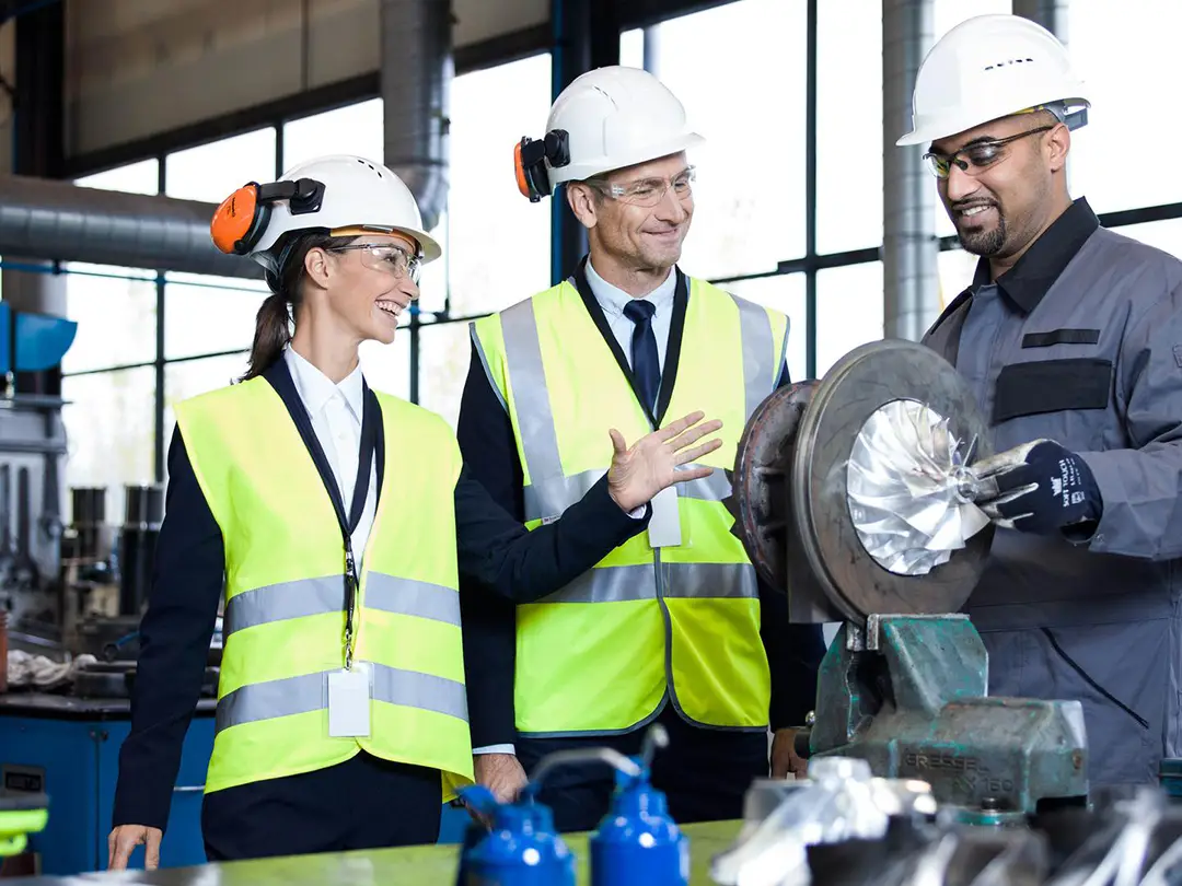 group of people in a workshop looking at a turbine