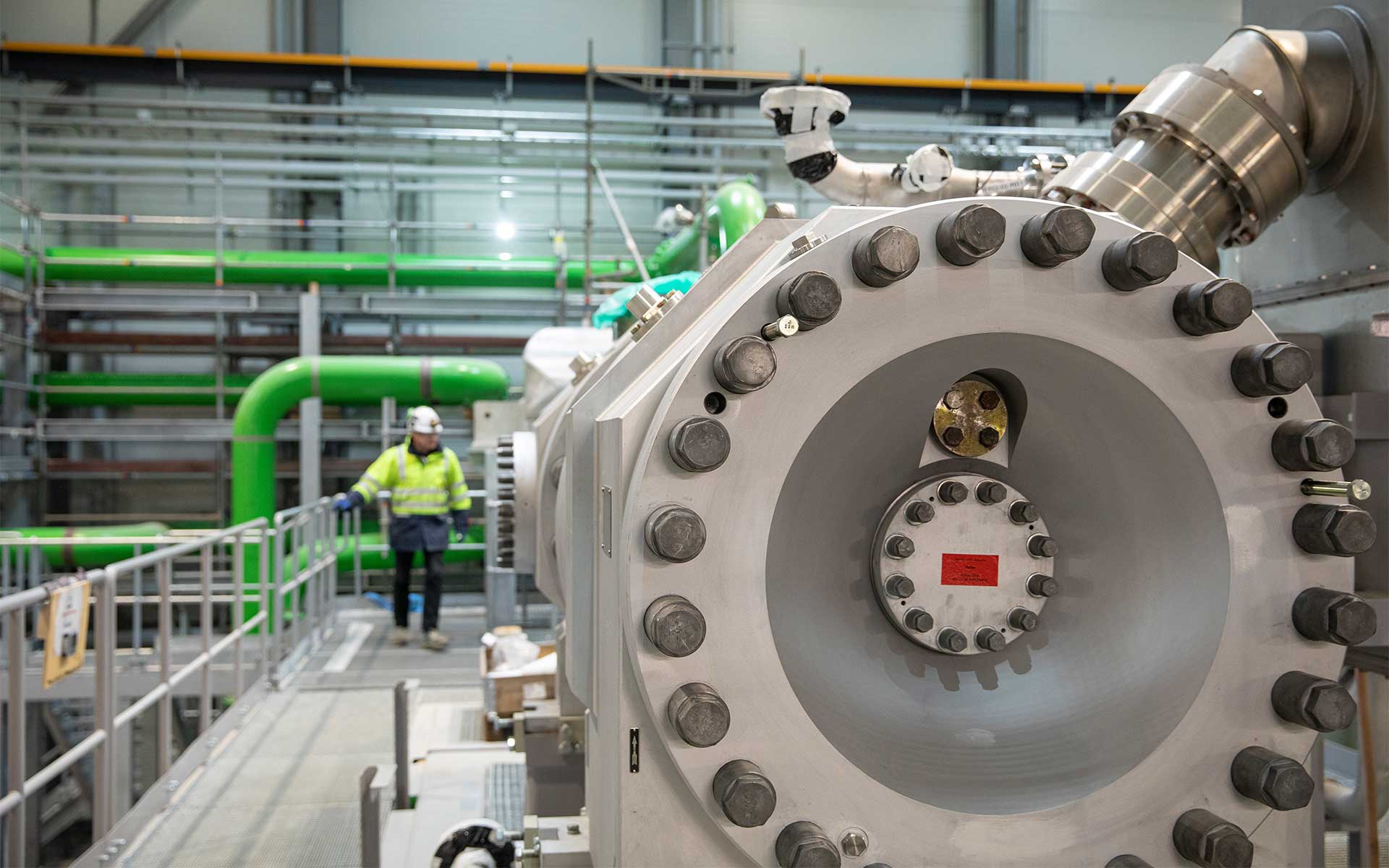 Large industrial heat pump in Esbjerg with focus on metallic surface and worker in background