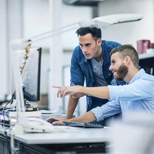 Two employees looking at a computer screen in front of them
