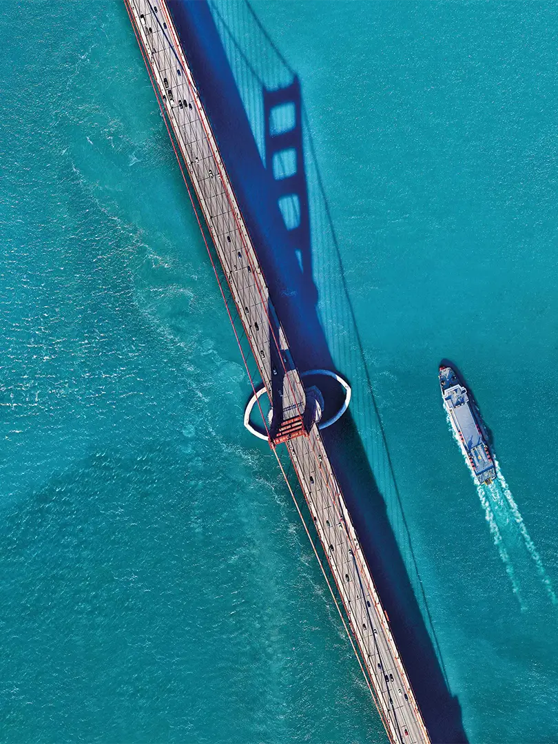 araial view of a suspension brigde and a ship passing by