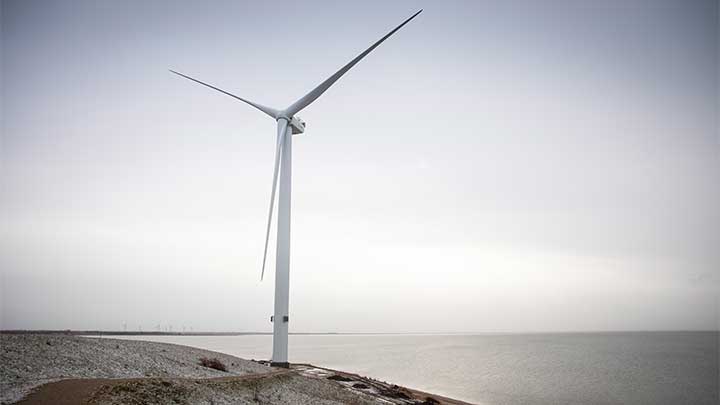 Single wind turbine by the coast with others visible in the distance on a grey, overcast day