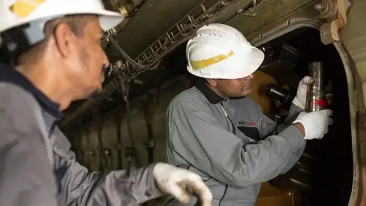 two service employees working at an engine