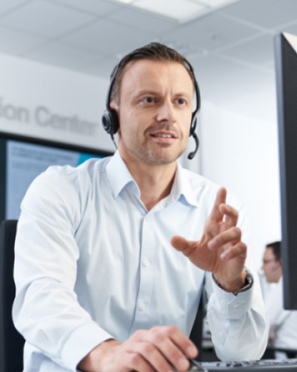 Support agent wearing a headset speaking at a computer.