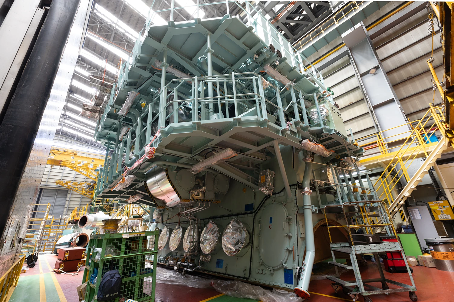 Massive ammonia engine mounted in a test facility, showing multiple cylinder units and structural platforms inside an industrial hall.