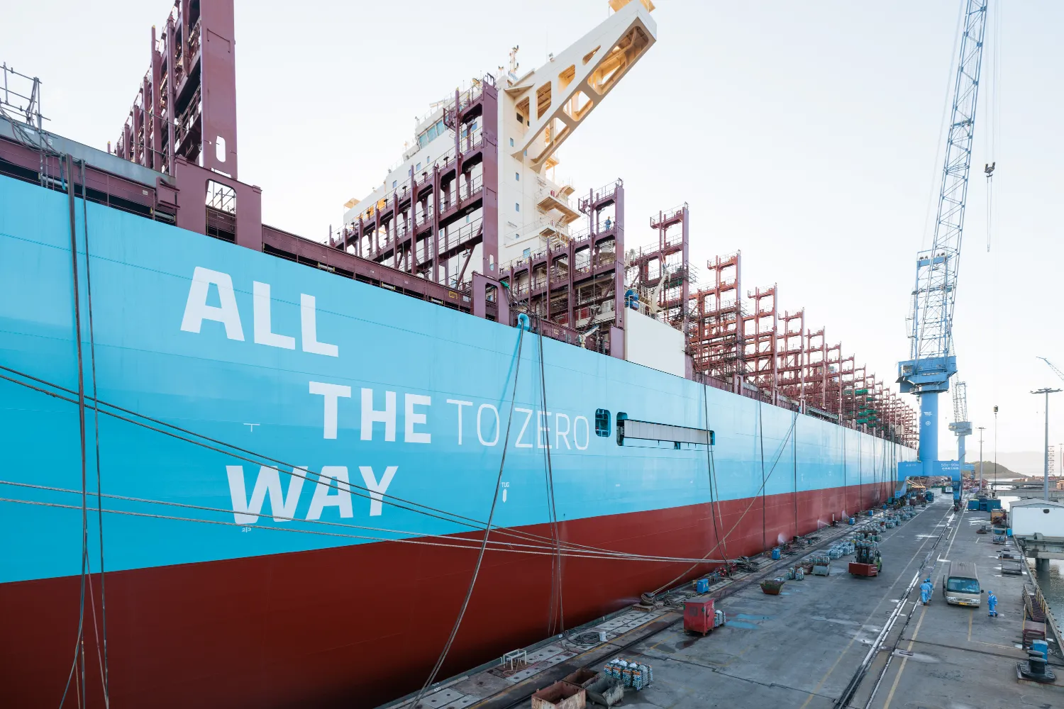 Cargo ship docked at port with the slogan “ALL THE WAY TO ZERO” painted on its side, symbolizing Maersk’s commitment to sustainable shipping.