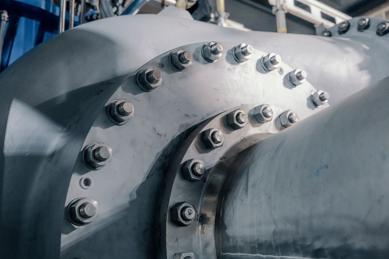Close-up of a metallic industrial pipe component with bolts and nuts securing two sections, part of Heidelberg Materials’ carbon capture system.