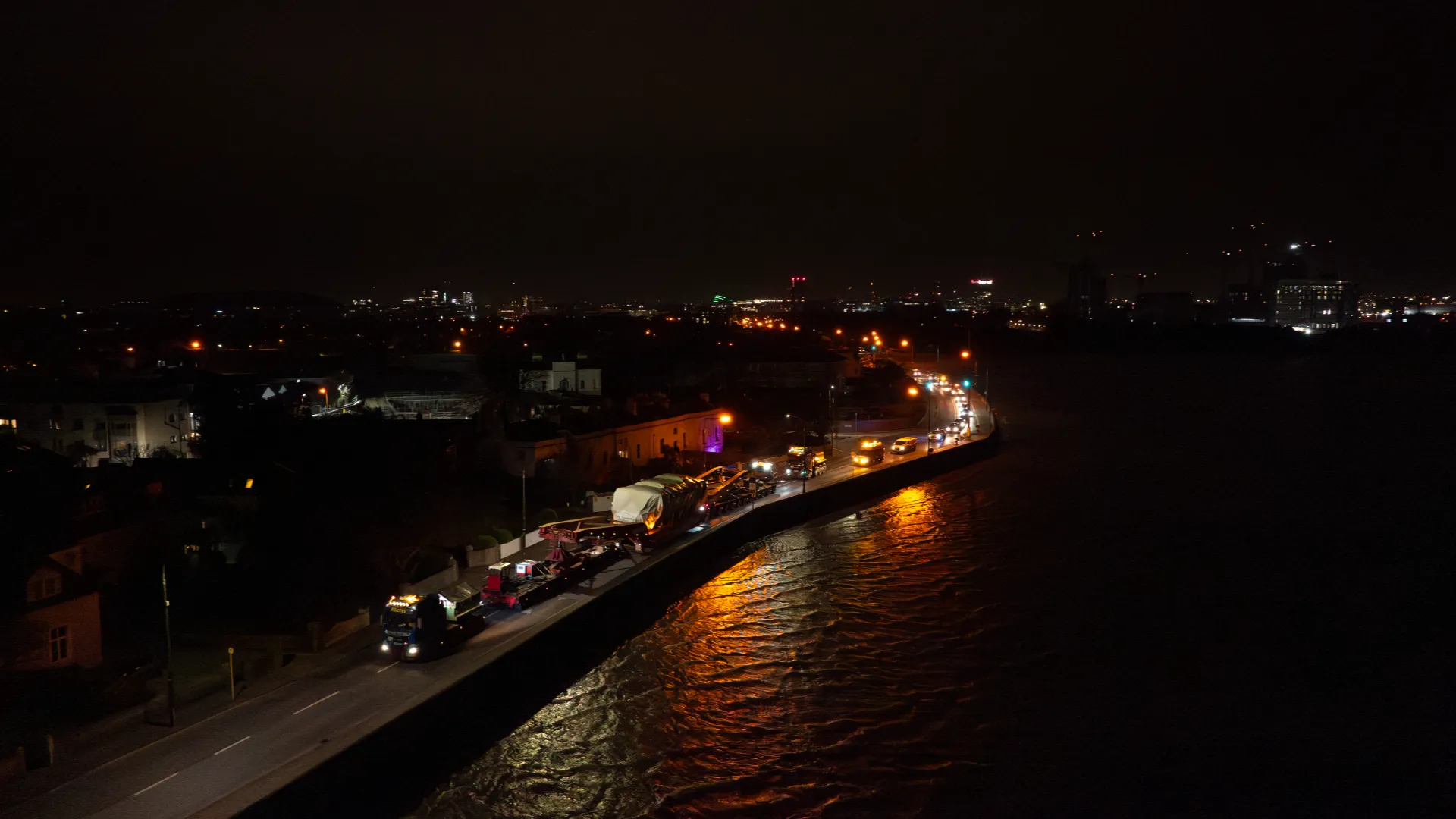 The illuminated convoy travels along Dublin’s coastal road at night.