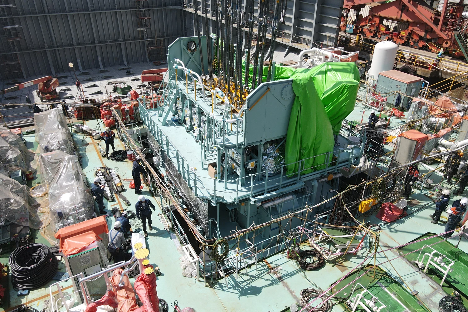 Overhead view of final ammonia engine sections being positioned inside a vessel under construction using cranes and lifting equipment.