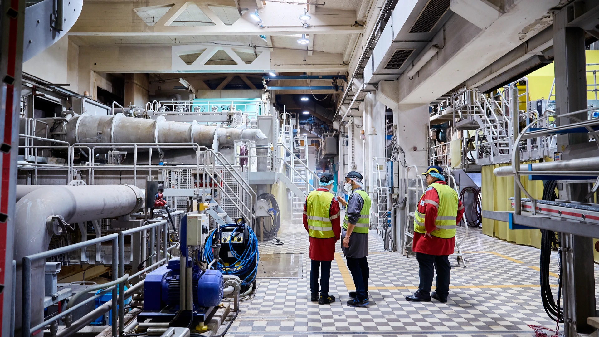 Team members inspecting equipment inside the paper mill’s production hall.