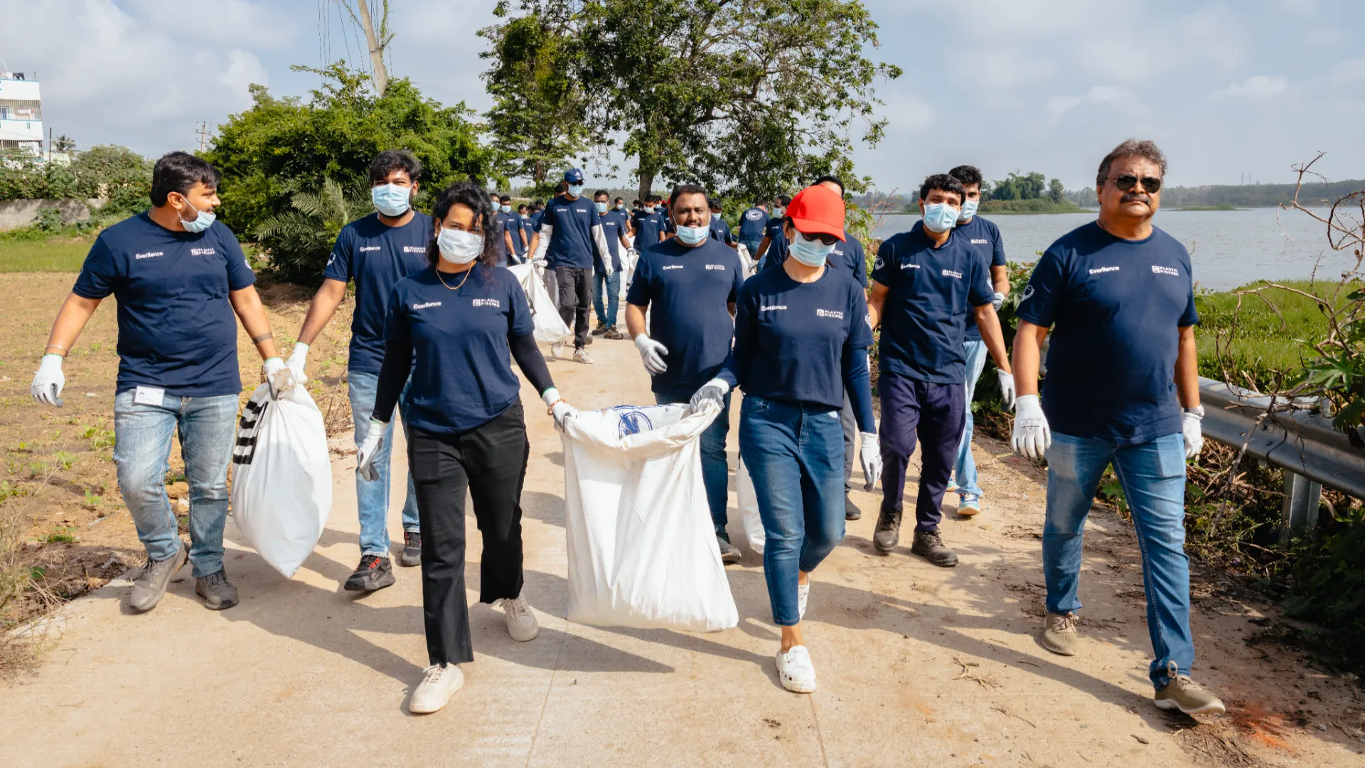 Group of Everllence employees carrying filled trash bags during a clean-up walk near Jigani Lake, Bengaluru.