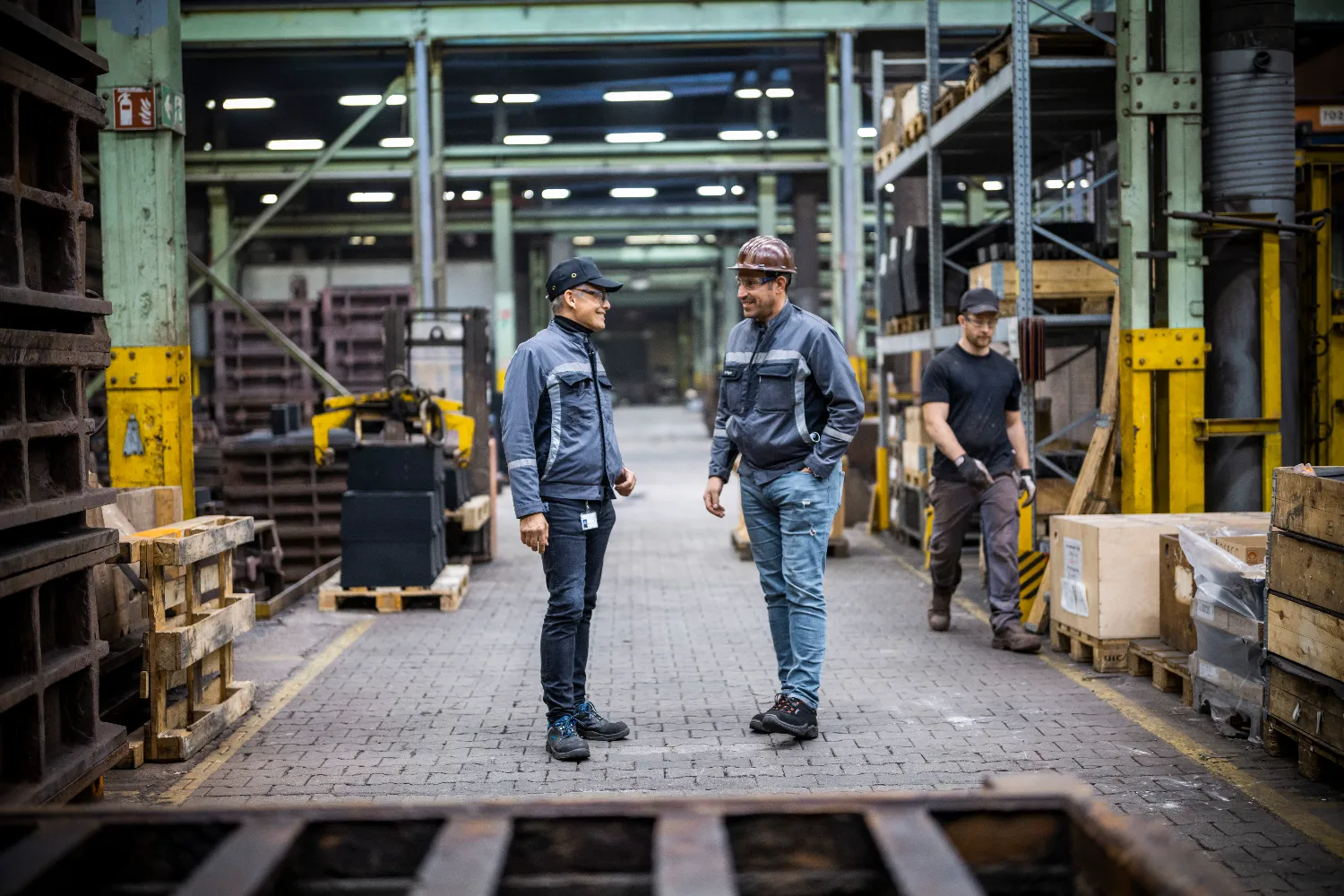 Manager Stephan Briehl and Head of Foundry Business Marco Nagler talking inside the foundry with industrial equipment in the background
