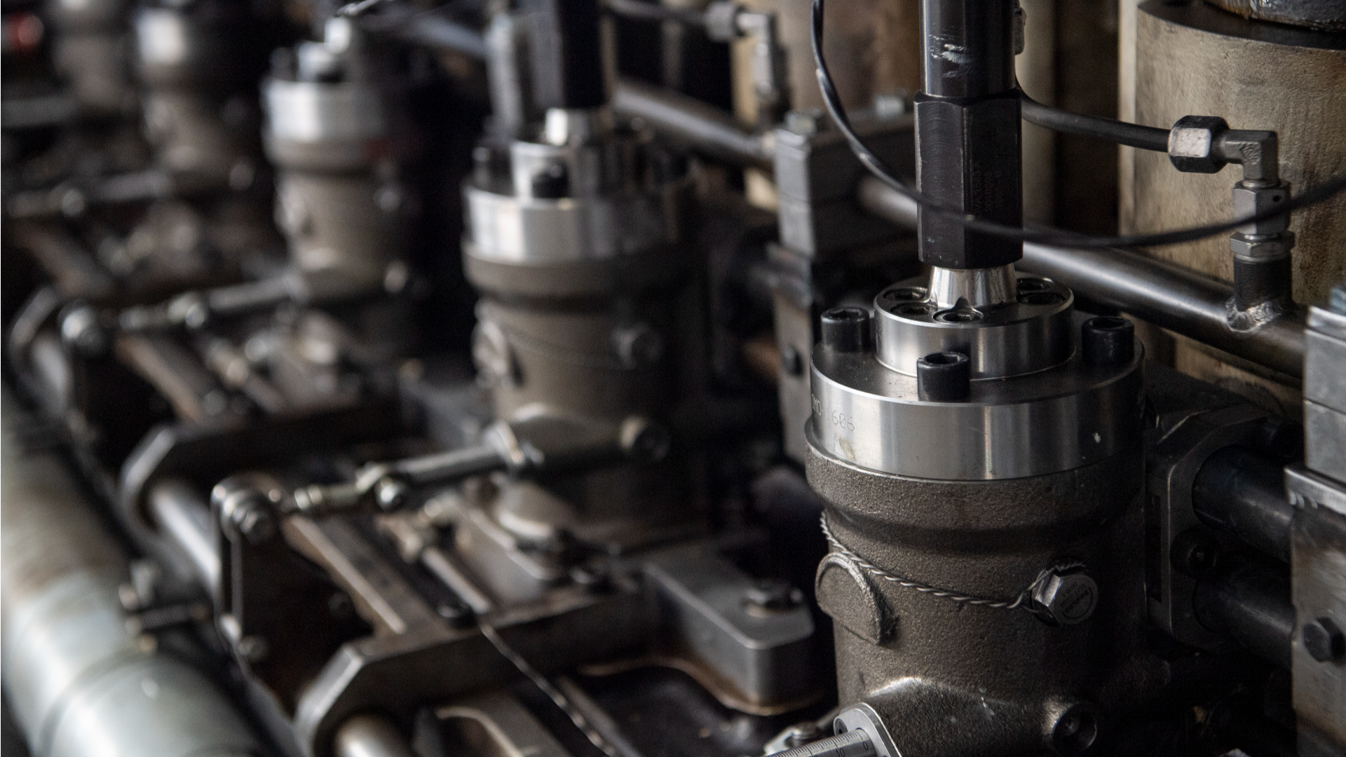 Close-up of metallic fuel injection components with valves, bolts, and connected pipes inside a methanol engine system