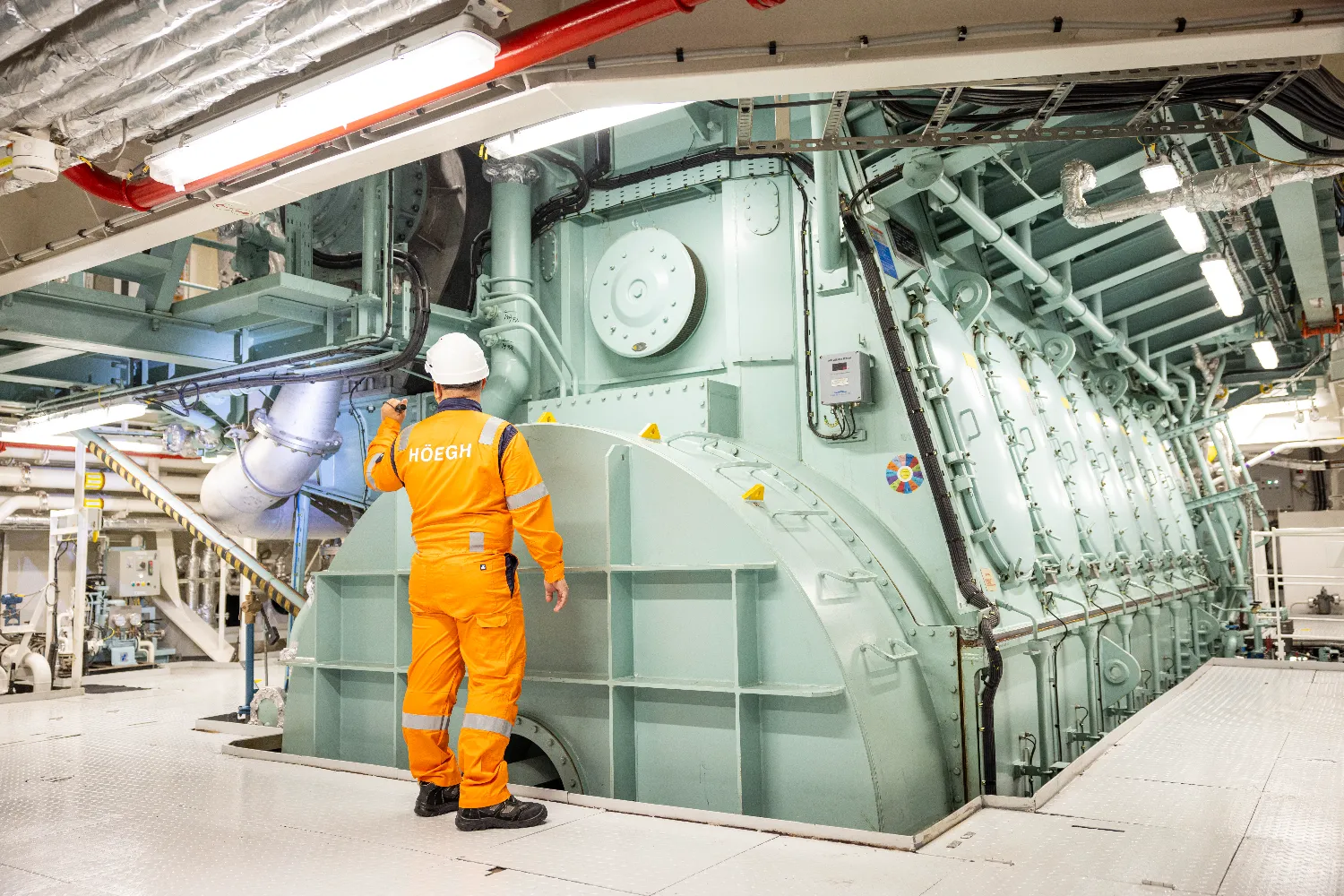 A crew member walks past the Everllence B&W ME-GI dual-fuel engine, showcasing the scale and complexity of methane-based propulsion technology.