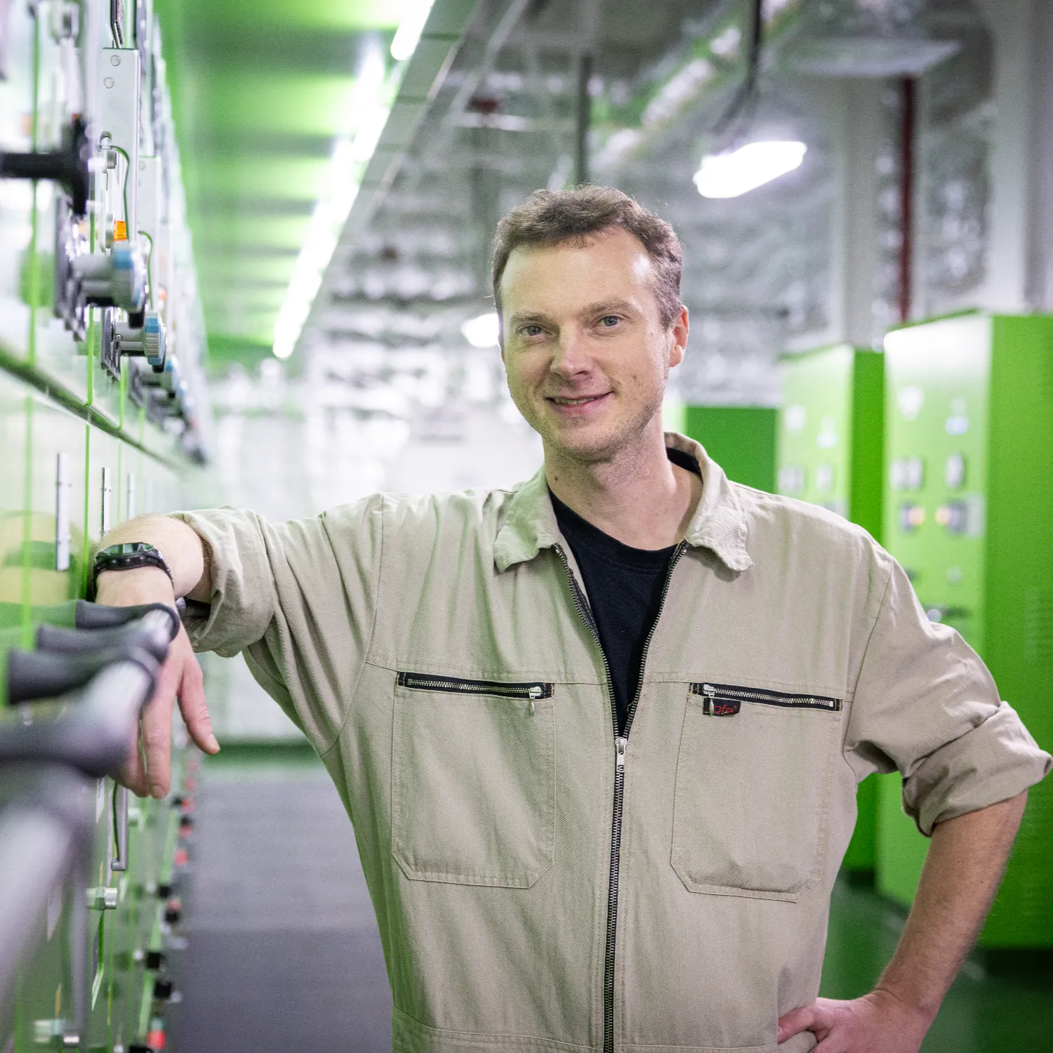 Ansgar Lehmkoester leaning against control panels in the engine room of the Hamburg Express, surrounded by green machinery and industrial equipment.