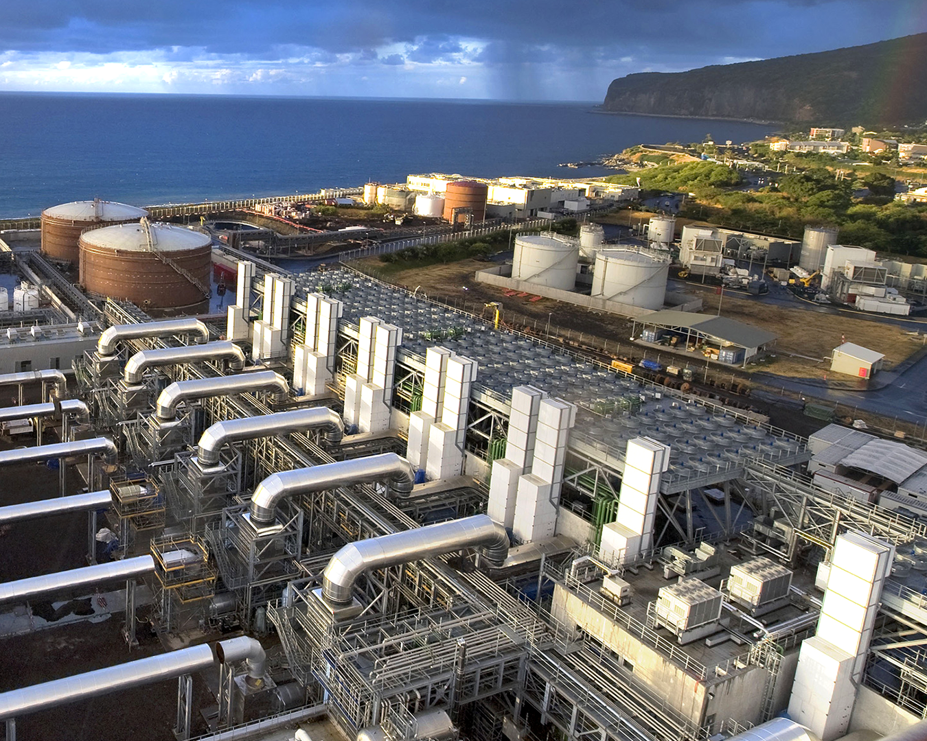 Modern coastal power plant with extensive piping system and ocean backdrop
