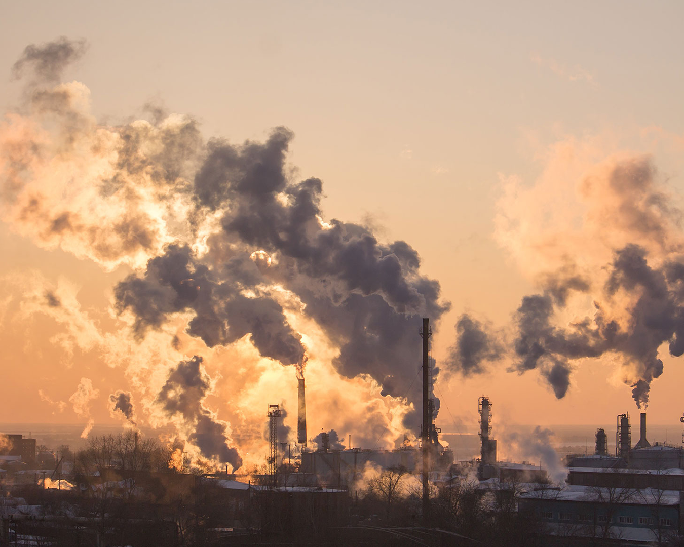 Industrial facility with smoke emissions at sunset sky