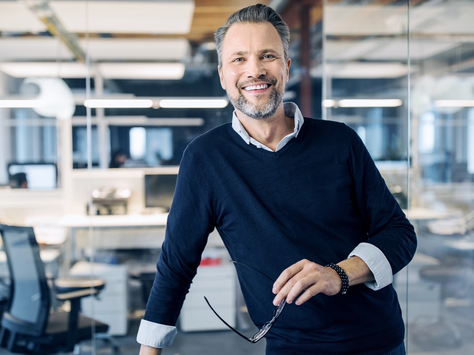 Smiling businessman in a modern glass office environment