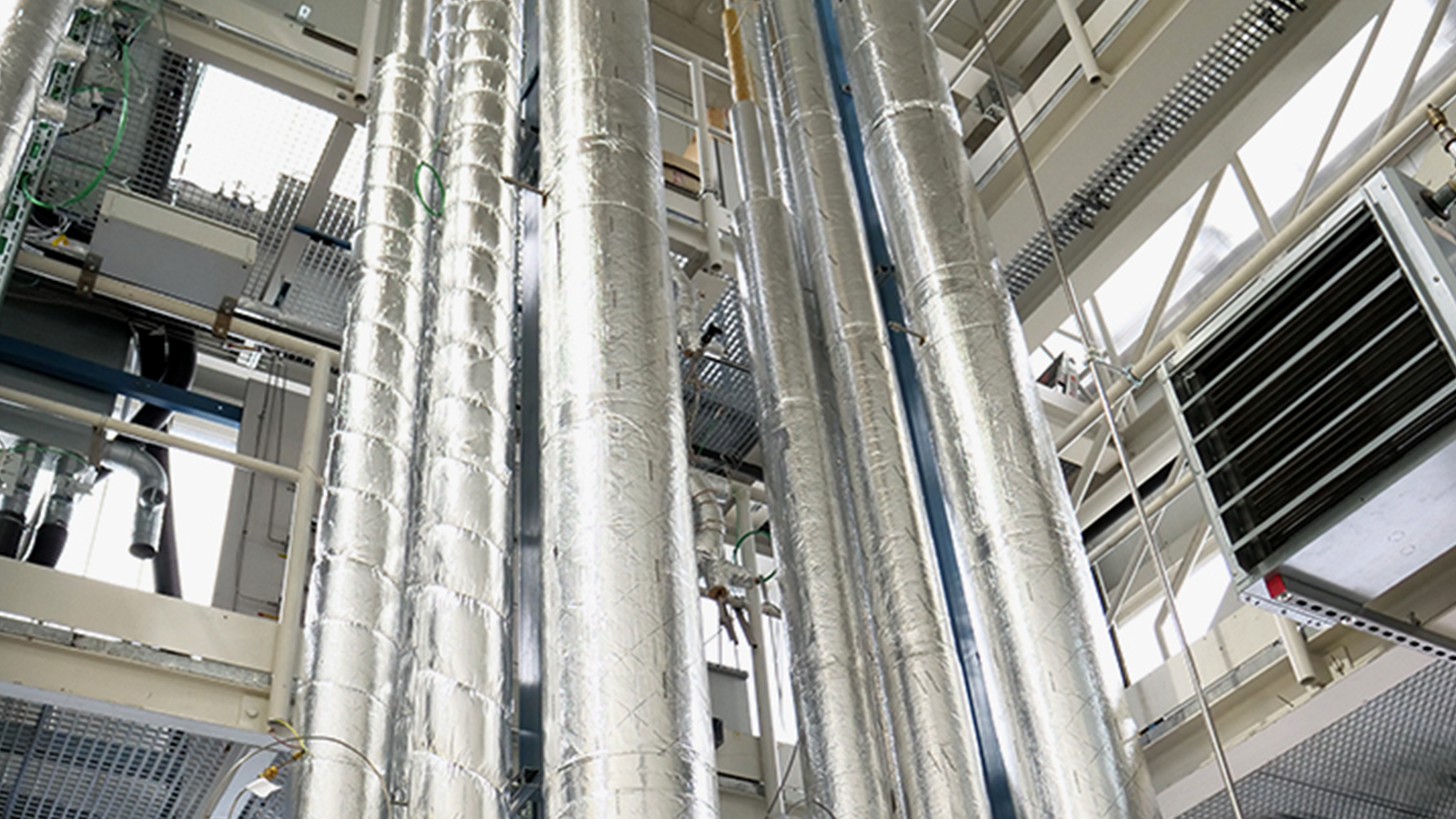 Pilot-scale RWGS unit with silver tanks and green pipelines inside a modern facility