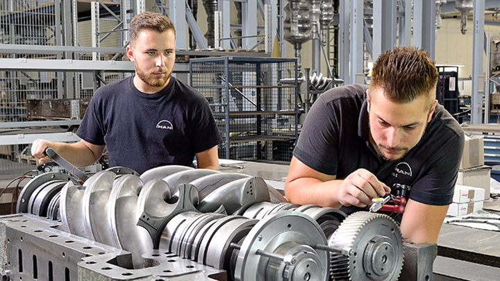 Focus on Availability Two technicians inspecting a screw compressor unit in a production environment