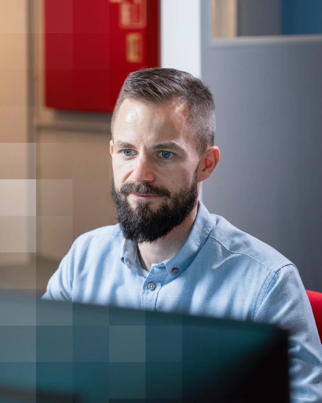 Bearded man focused on a laptop in an office setting