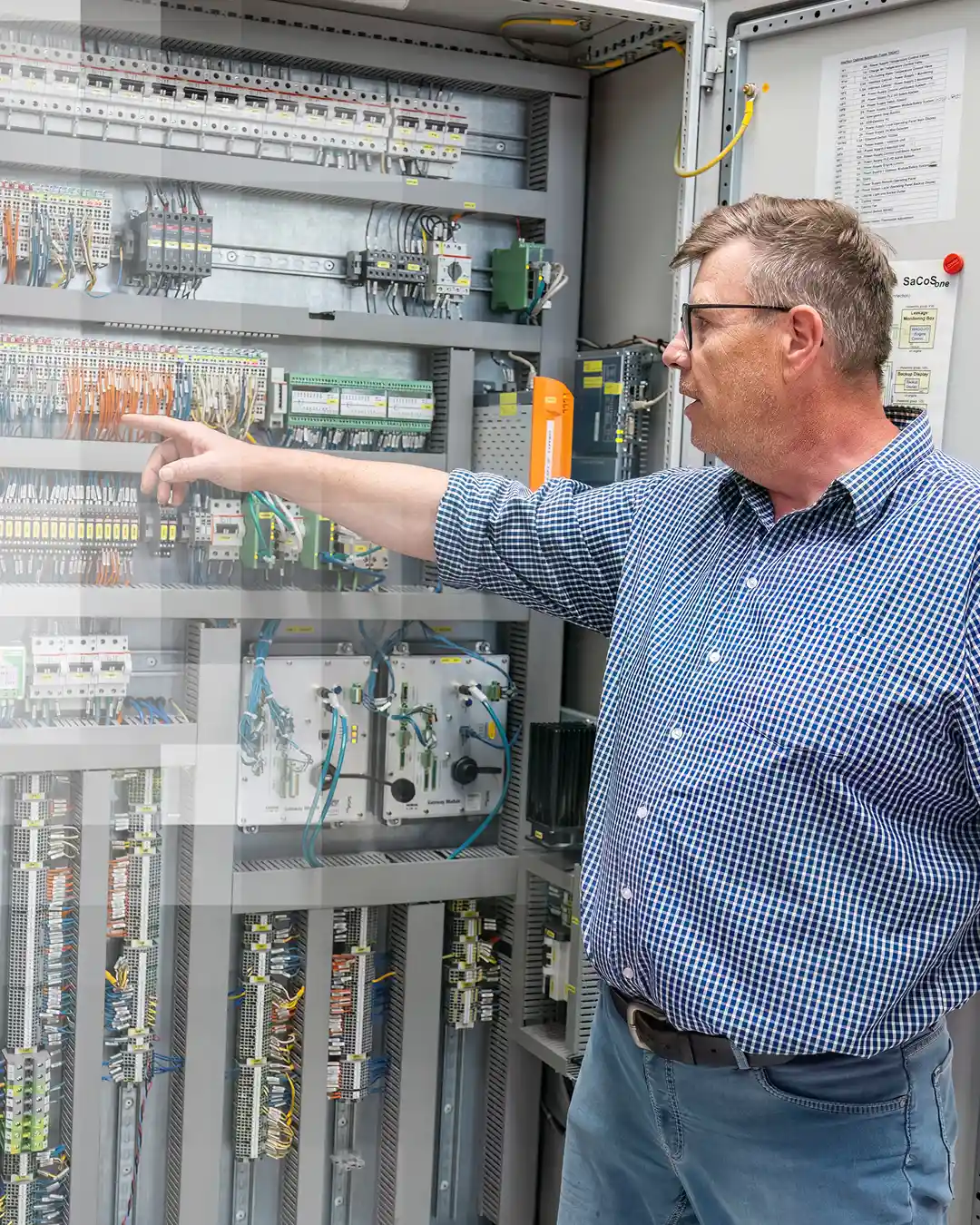 Expert pointing at an open electrical control cabinet.