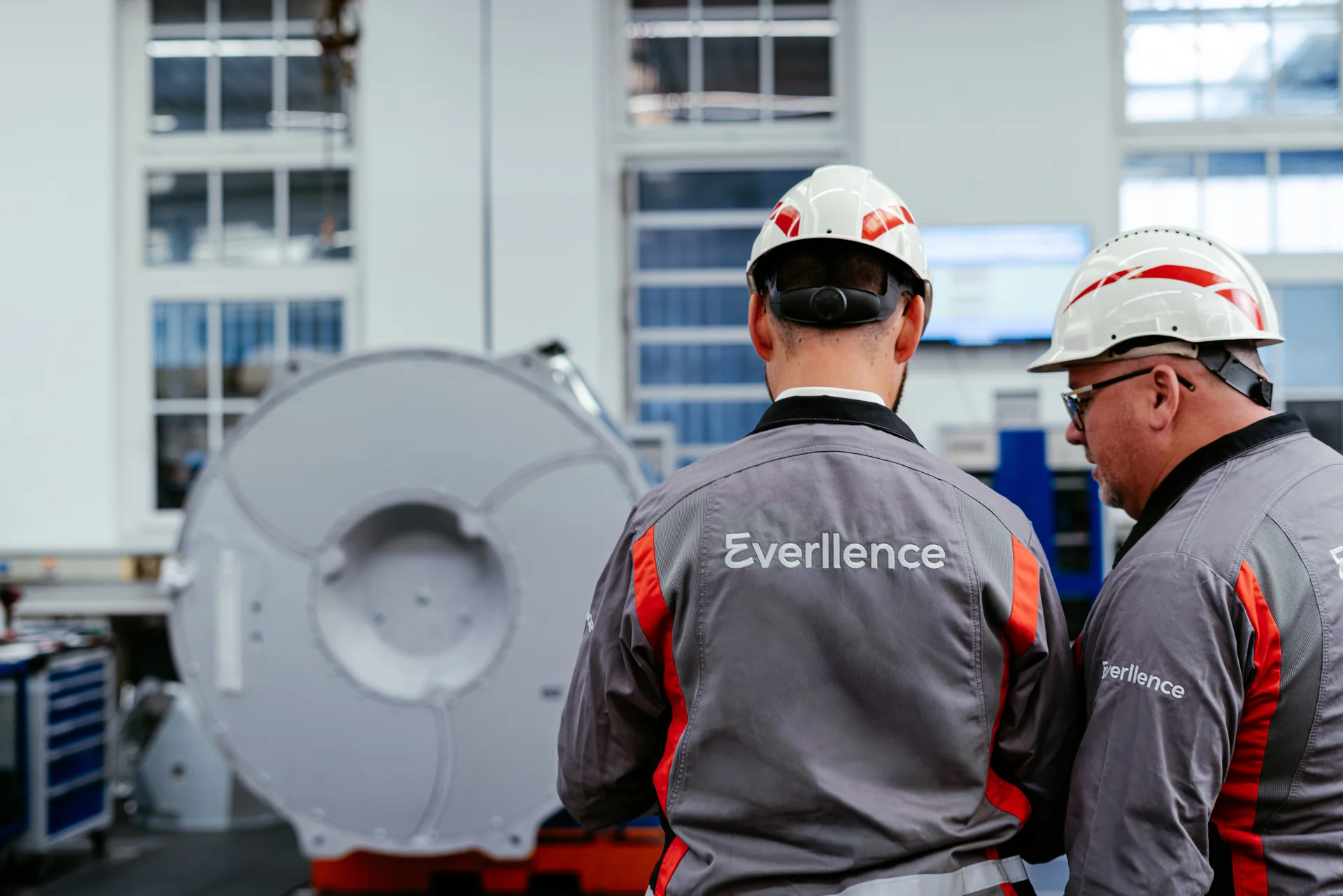 Two Everllence engineers in front of a turbocharger facing towards it