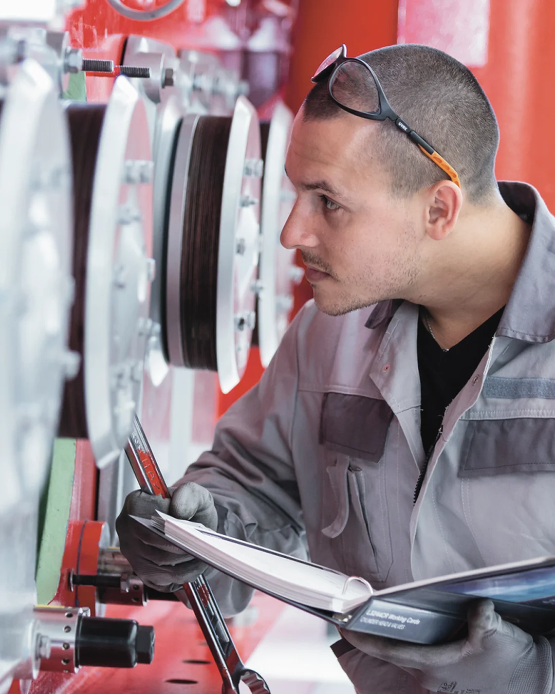 Technician writing in a notebook while inspecting mechanical components