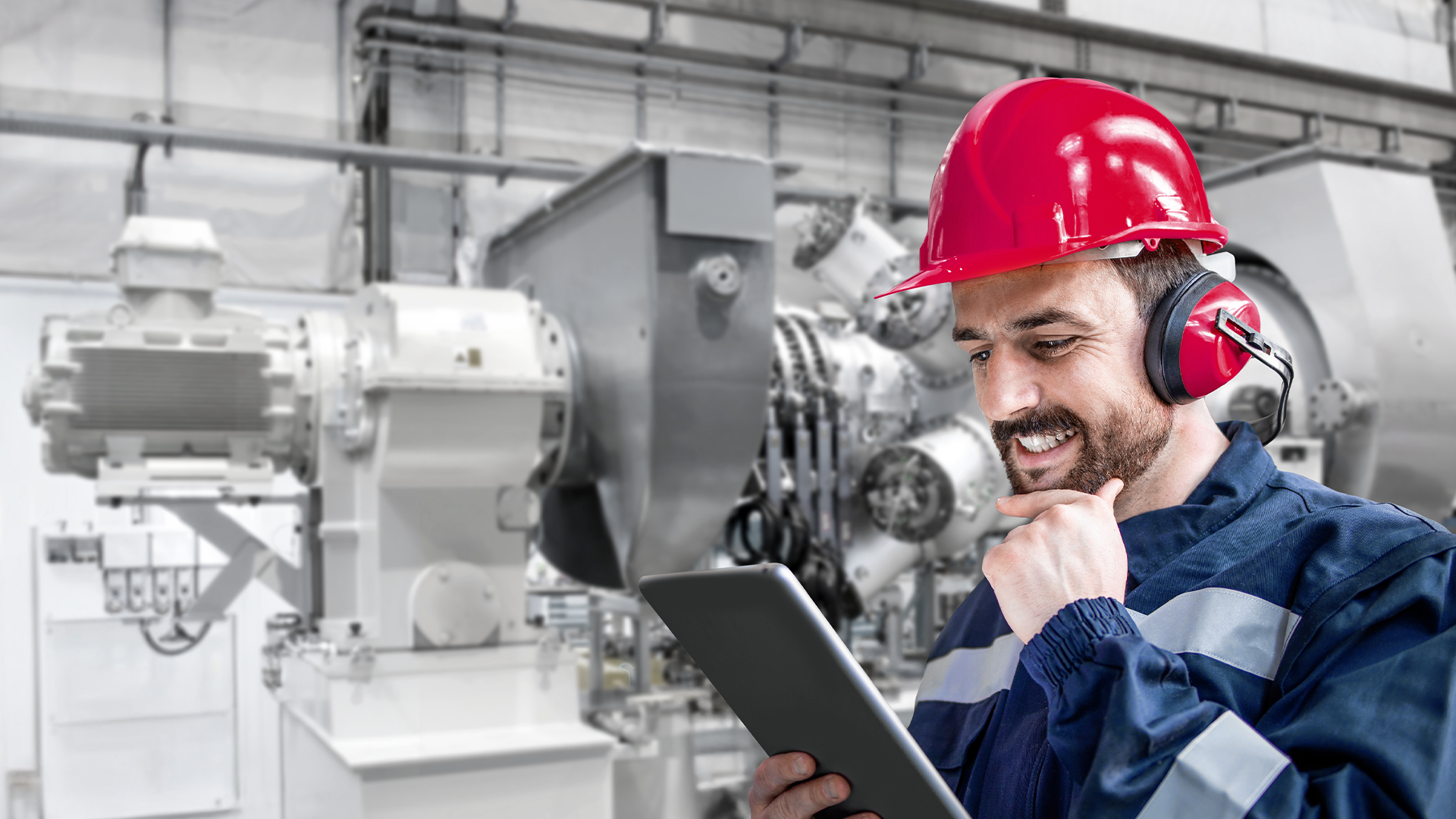 Visual of a smiling man with an iPad in front of a gas turbine