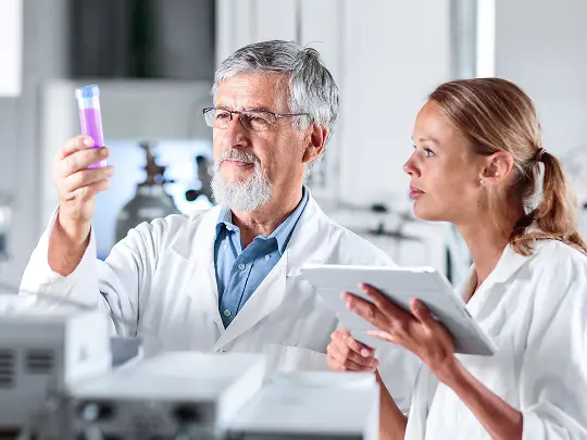 Man and woman in lab coats looking at a test tube